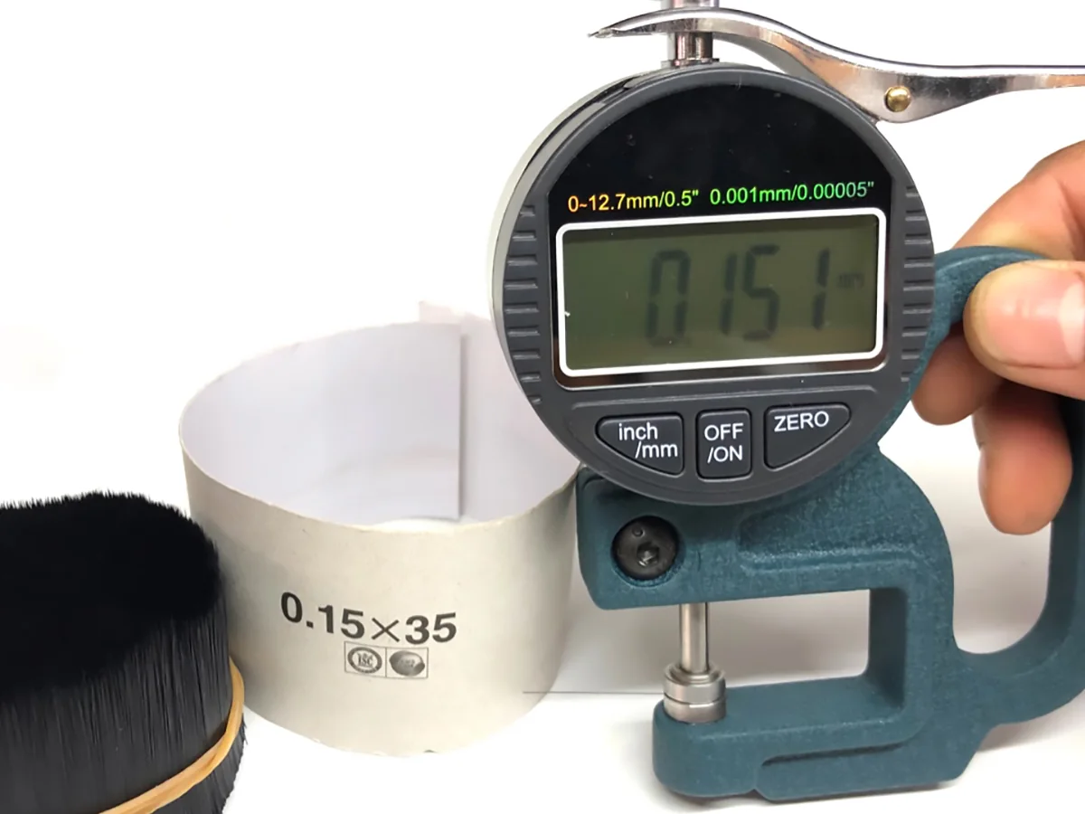 Medidor digital marcando 0.151 mm em uma fileira de cílios flat durante a conferência do lote